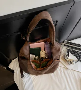 Interior espacioso del bolso de ante marrón con tableta y objetos cotidianos
