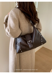 Detail of vintage brown leather tote bag featuring silver rivets and metal buckle closure