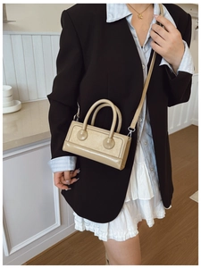 Khaki leather crossbody bag shown on a model in a minimalist stylish office setting