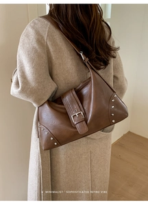 Close-up of brown retro tote bag with wide metal buckle and silver rivet details