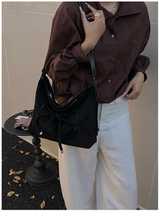 Detail view of the black frosted tote bag with white stitching and knot drawstring accents