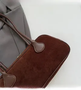 Macro shot of dark brown frosted suede texture and long handle on minimalist bowling bag