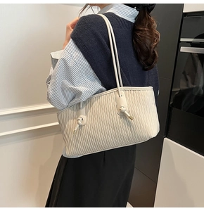 Detailansicht der beigen Tragetasche mit eleganter Wellenfaltenstruktur und Trägern