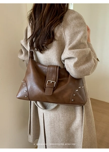 Detail of retro dark brown leather tote with silver studs and buckle on model