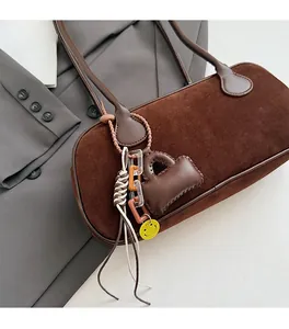 Detail of brown faux suede baguette bag featuring stylish charms and premium strap