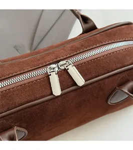 Detailed macro view of the dual metal zippers and reinforced brown leather handle base