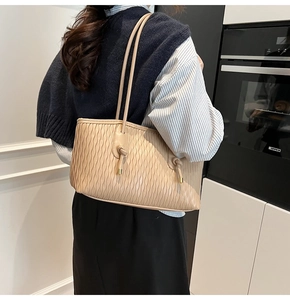 Gros plan détaillé du sac cabas beige plissé avec doubles bretelles et détails de nœuds