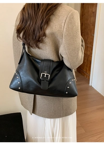 Close-up of black retro leather tote with belt buckle detail and silver studs on side