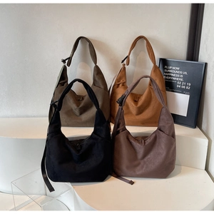 Detalle lateral de bolsos hobo de ante con correas anchas y hebillas metálicas ajustables