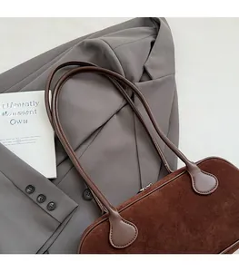 Detail of dark brown suede baguette bag with leather strap and soft velvet texture