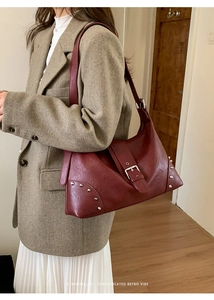 Detail of dark red tote bag featuring silver studs and glossy vintage leather finish