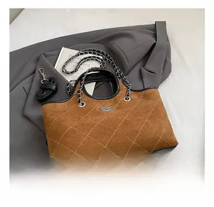 Detail of brown quilted tote bag with silver chain handle and metal twist lock