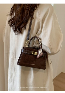 Detalle del bolso Kelly de ante marrón oscuro con hebilla dorada y pañuelo de seda