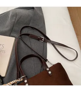 Detail of dark brown suede bucket bag featuring silver buckles and woven rope charm