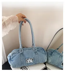 Close-up of blue denim boston bag with vintage metal logo plate and double handles