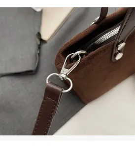 Close-up of premium silver-tone hardware and suede texture on a vintage brown bucket bag