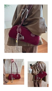 Detail of burgundy velvet baguette bag with heart charm and tassel, vintage 2025 style