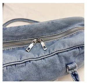 Detailed close-up of smooth silver dual metal zippers on light blue denim tote bag
