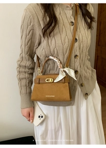 Detalle de bolso de ante marrón con asa de pañuelo de seda y cierre metálico elegante