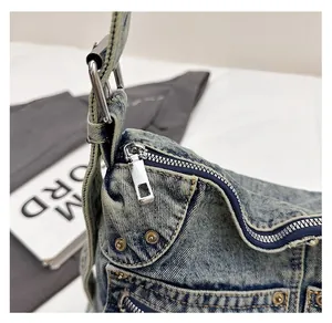 Gros plan sur les fermetures éclair en métal et le denim délavé du sac cabas rétro