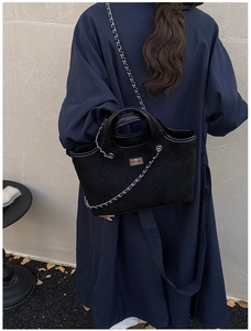 Detailed view of black quilted tote bag with silver chain strap and metal turn-lock