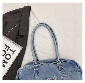 Detail of vintage washed blue denim tote with raw edges and circular metal handle
