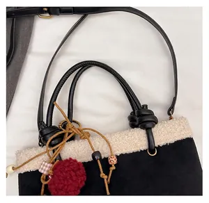 Detail der Winter-Wildledertasche mit weißem Plüschbesatz und rotem Bommel-Accessoire