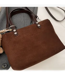 Detailed texture of dark brown suede handbag with silver studs and a plush keychain