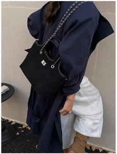Detail of black quilted suede tote bag featuring silver twist lock and chain strap