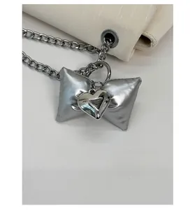 Macro view of silver bow charm with heart-shaped metal buckle on a textured chain
