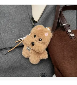 Detail of a plush dog bag charm with TOP DOG bone tag on a brown suede bucket bag