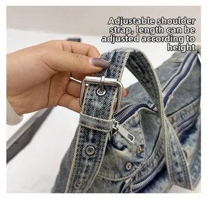 Détail d'une bandoulière en denim délavé réglable avec boucle métallique argentée