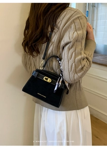 Detalle de bolso Kelly en ante negro con costuras blancas y pañuelo de seda atado