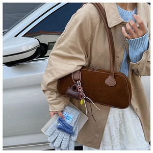 Detail of dark brown suede pillow bag with a mini charm on a stylish khaki trench coat