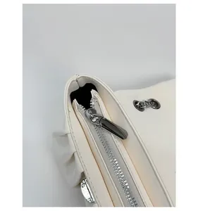 Close-up of smooth white leather bag featuring polished silver metal zipper and chain eyelets