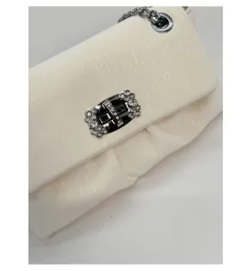 Detail of cream pleated fabric shoulder bag with sparkling rhinestone square lock