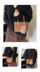 Detail of brown suede tote with leather handles and cute plush puppy charm accessory