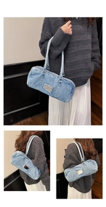 Detail of light blue washed denim tote bag with silver logo plate on frayed edge