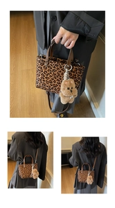 Detail of leopard print bucket bag with brown leather handles and plush dog charm