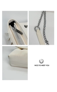 Detail view of cream shoulder bag featuring metal zipper, chain strap, and pleated texture