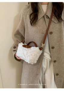 Detail of white faux shearling mini bag with brown leather handles and gold buckle