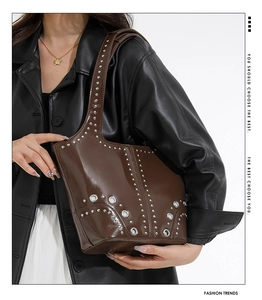Detail view of dark brown punk shoulder bag with silver studs and eyelet decorations