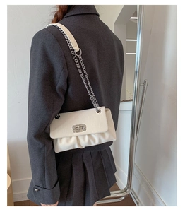 Detail of white pleated shoulder bag with silver chain strap and sparkling twist lock