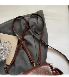 Détail d'un sac à bandoulière en cuir marron foncé brillant avec de fines lanières