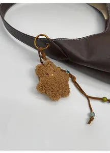 Detailed view of a brown plush star pendant with colorful beads on a leather bag handle