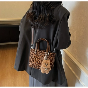 Dettaglio della borsa a tracolla leopardata con ciondolo a orsetto indossata dal modello