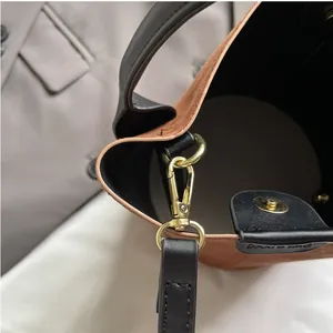 Macro view of brown frosted suede bucket bag with gold lobster clasp and magnetic closure