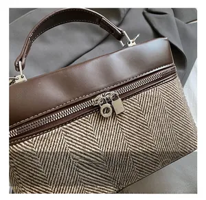 Detail of silver zipper and herringbone fabric on a brown leather handbag