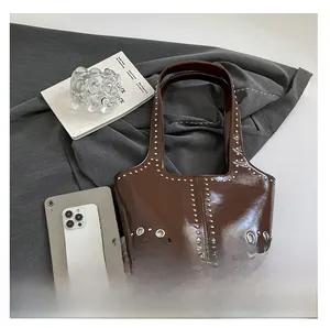Vista dettagliata della borsa tote marrone lucida con borchie argentate e grandi occhielli
