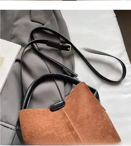 Close-up of adjustable black leather strap with gold buckle on brown suede bucket bag